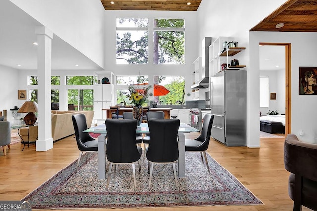 dining room with recessed lighting, light wood finished floors, and a towering ceiling