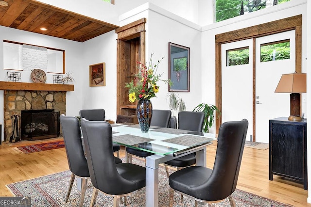 dining room featuring light wood-style floors, recessed lighting, wood ceiling, and a stone fireplace