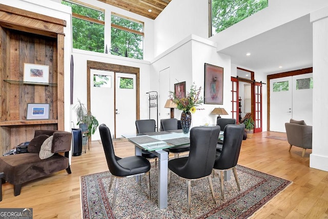 dining area with high vaulted ceiling, french doors, and light wood finished floors