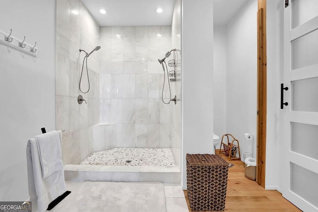 full bathroom featuring recessed lighting, toilet, tiled shower, and wood finished floors