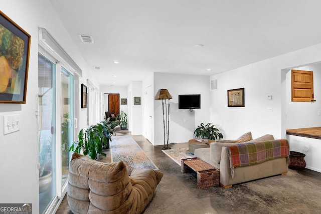 living room with finished concrete floors, recessed lighting, and visible vents