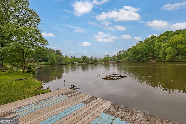 view of dock with a water view and a wooded view