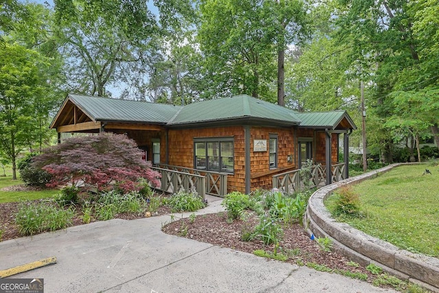 view of front facade with a porch, metal roof, and a front yard