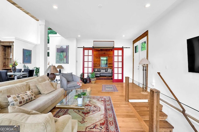 living area with light wood-style floors, a barn door, and recessed lighting