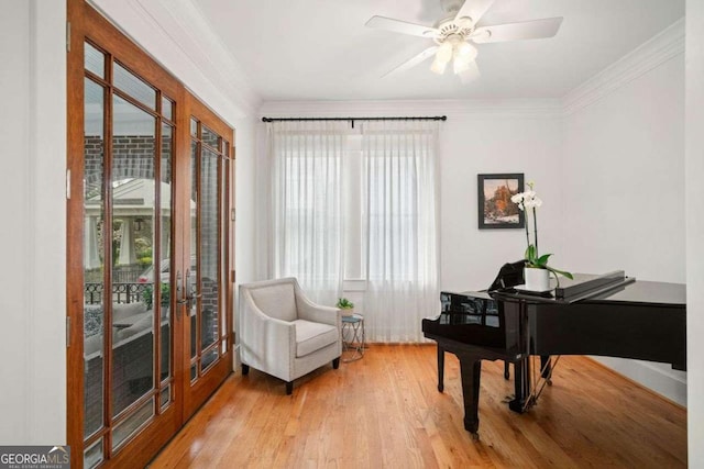 living area featuring french doors, wood finished floors, ornamental molding, and a ceiling fan