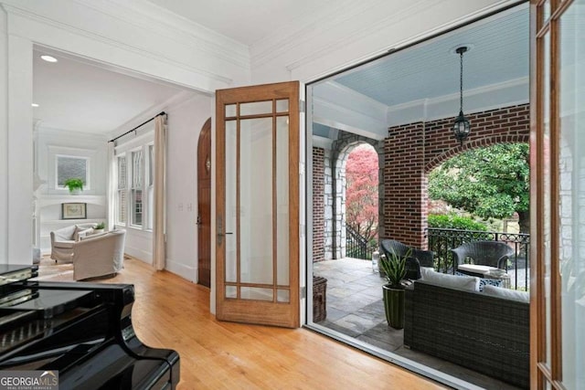 interior space featuring ornamental molding, brick wall, and wood finished floors
