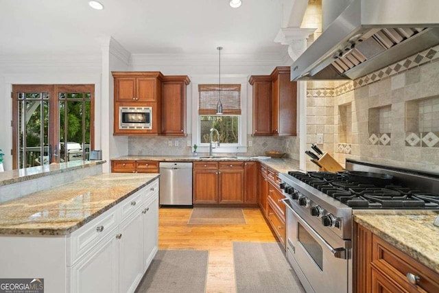 kitchen with a sink, wall chimney exhaust hood, appliances with stainless steel finishes, and brown cabinetry