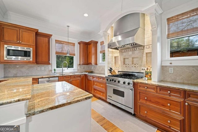 kitchen featuring a sink, wall chimney exhaust hood, appliances with stainless steel finishes, light wood-style flooring, and ornamental molding
