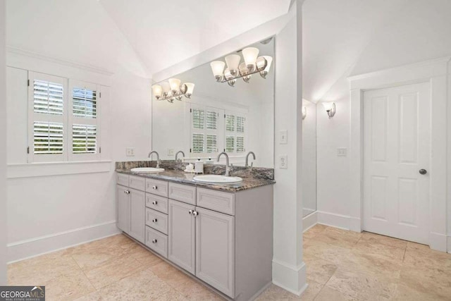bathroom featuring a chandelier, double vanity, a sink, and vaulted ceiling