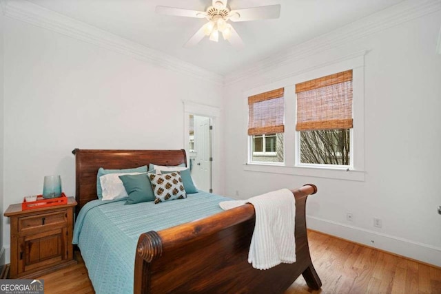 bedroom with baseboards, light wood-type flooring, crown molding, and ceiling fan