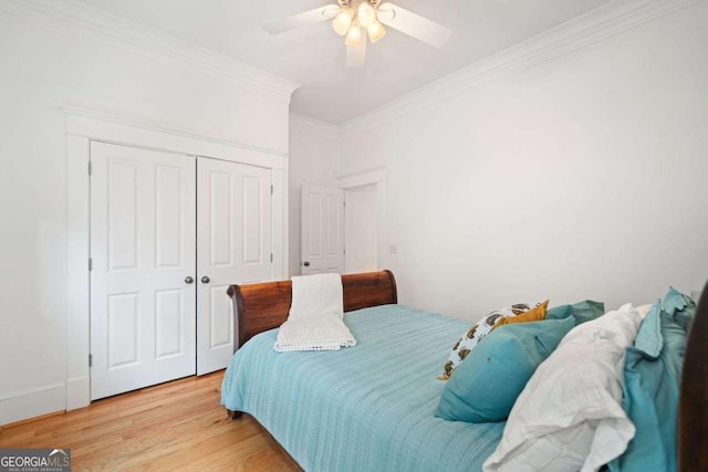 bedroom featuring light wood finished floors, a closet, ornamental molding, and a ceiling fan
