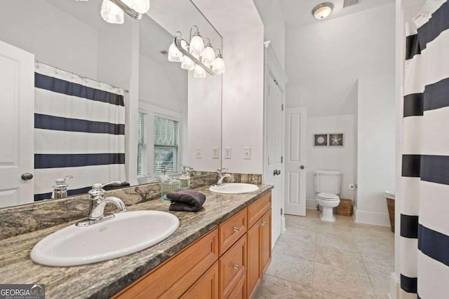 full bathroom with baseboards, double vanity, a sink, and toilet