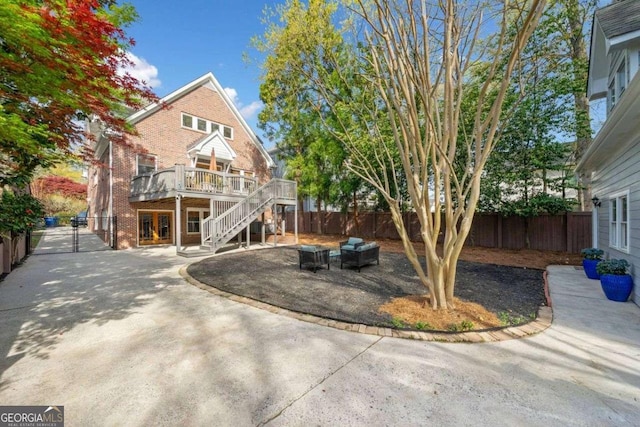 exterior space featuring fence, a wooden deck, a patio, stairs, and brick siding
