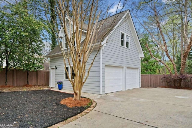 view of property exterior with driveway, fence, a garage, and roof with shingles