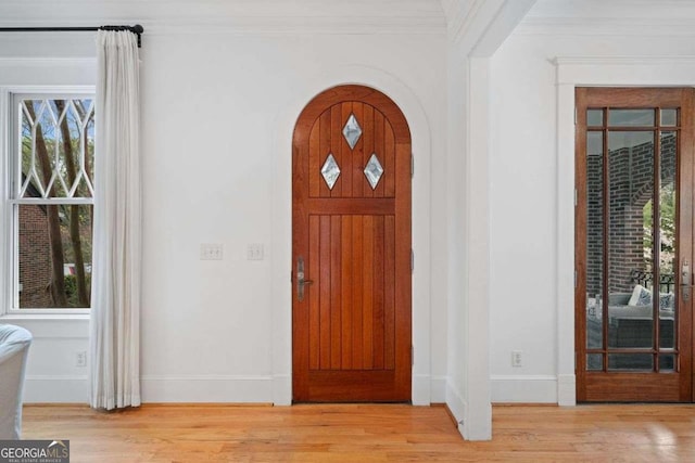 entryway with ornamental molding, arched walkways, baseboards, and wood finished floors