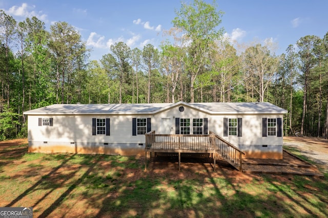 back of property featuring a wooden deck, crawl space, and a wooded view