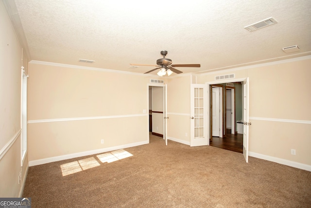 unfurnished bedroom with ornamental molding, a textured ceiling, visible vents, and carpet