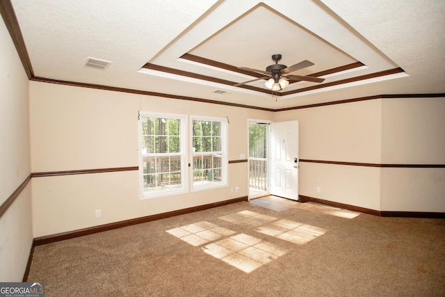 carpeted empty room featuring a raised ceiling, visible vents, crown molding, and ceiling fan