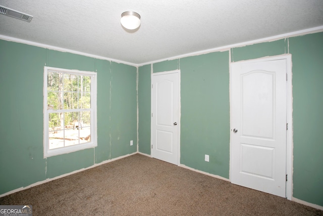 unfurnished bedroom with a textured ceiling, carpet floors, and visible vents