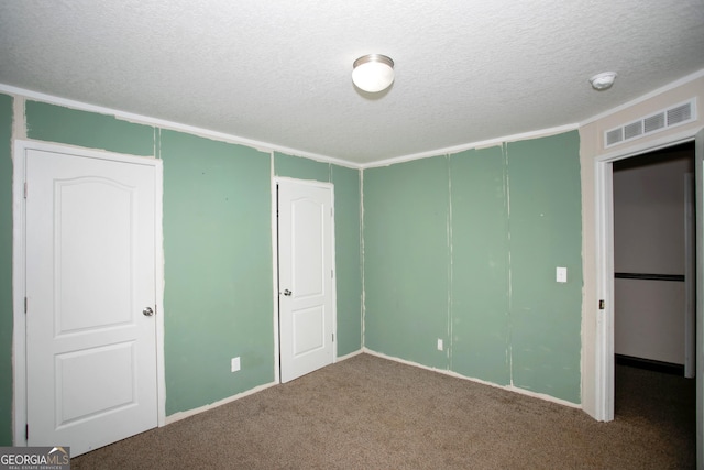 unfurnished bedroom featuring visible vents, carpet, a textured ceiling, and a closet