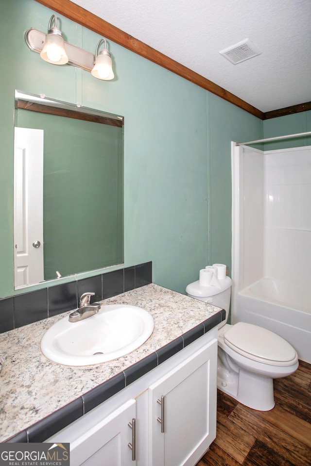 full bathroom featuring wood finished floors, visible vents, toilet, vanity, and ornamental molding