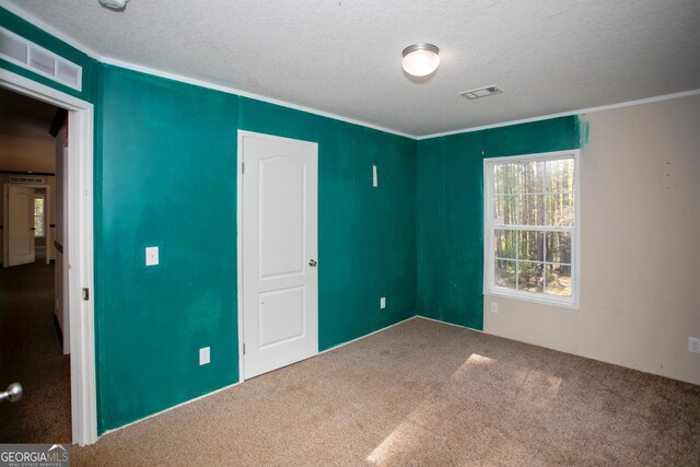 unfurnished bedroom featuring a textured ceiling, visible vents, and carpet flooring