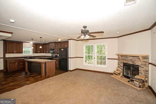 kitchen with a textured ceiling, open floor plan, visible vents, a kitchen island, and black appliances