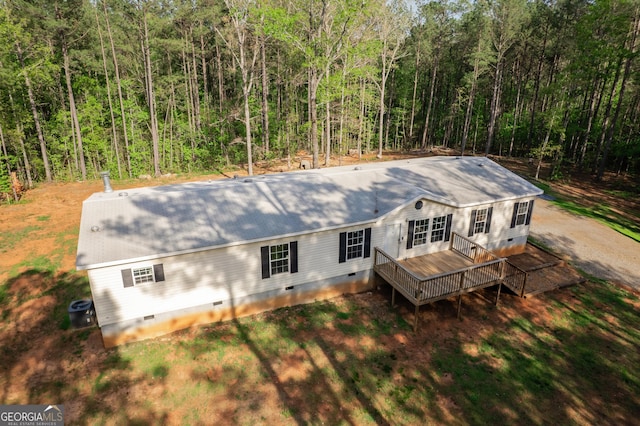 back of house with crawl space, a forest view, and a deck