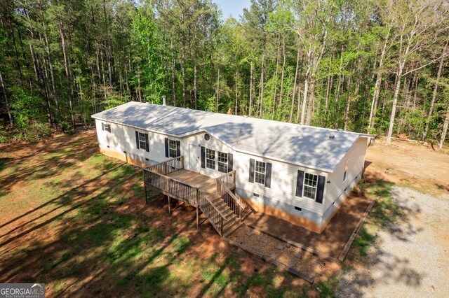 view of front of home with a wooden deck, crawl space, a wooded view, and stairway