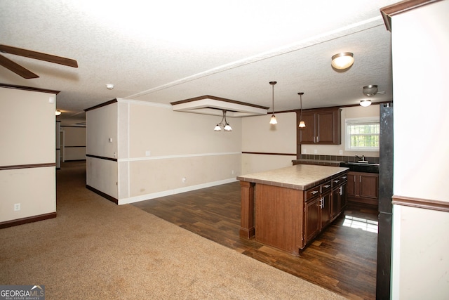 kitchen featuring a ceiling fan, a sink, a kitchen island, baseboards, and open floor plan
