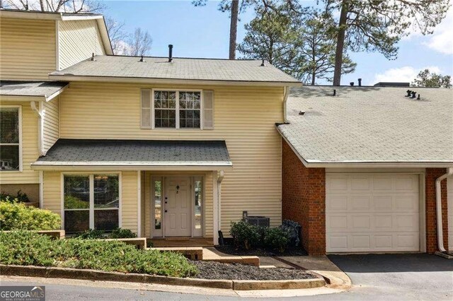 traditional-style house with brick siding, a garage, and aphalt driveway