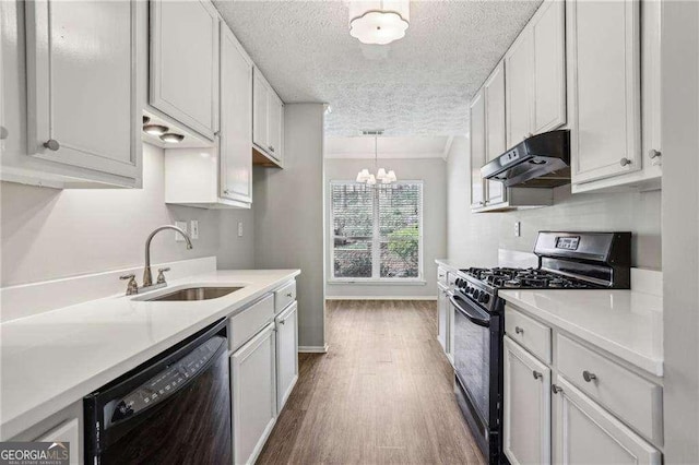 kitchen featuring a sink, wood finished floors, a textured ceiling, under cabinet range hood, and black appliances