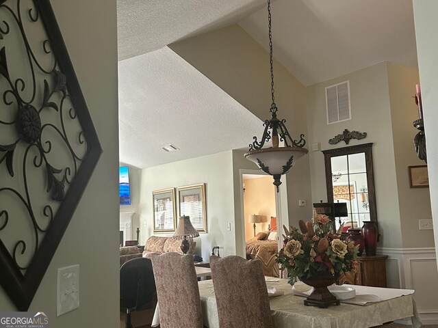 227 Fenwick Cir, Mcdonough, GA 30253 - dining room with lofted ceiling, plenty of natural light, a wainscoted wall, and a textured ceiling