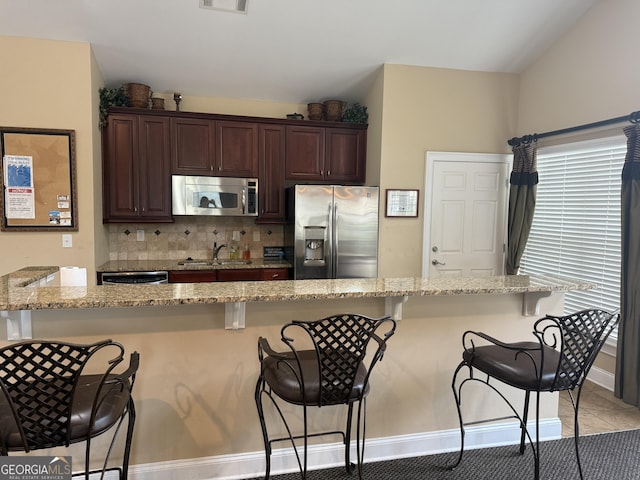 227 Fenwick Cir, Mcdonough, GA 30253 - kitchen with stainless steel appliances, a kitchen breakfast bar, light stone countertops, dark brown cabinets, and backsplash