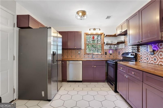 kitchen with butcher block countertops, backsplash, visible vents, stainless steel appliances, and a sink