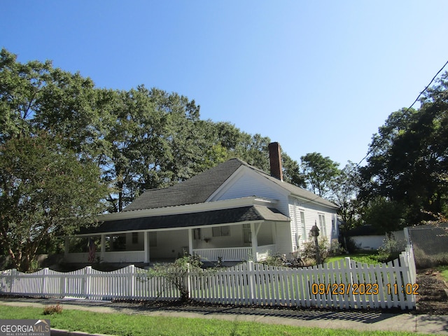 view of front of home with a shingled roof, a fenced front yard, and a chimney
