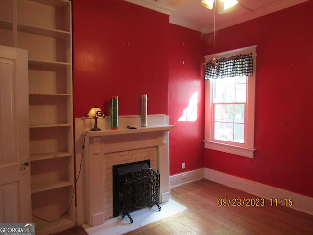 unfurnished living room with baseboards, a fireplace, ornamental molding, wood finished floors, and a ceiling fan