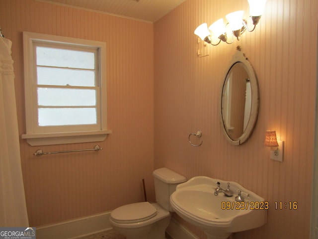 bathroom featuring baseboards, toilet, ornamental molding, and a sink