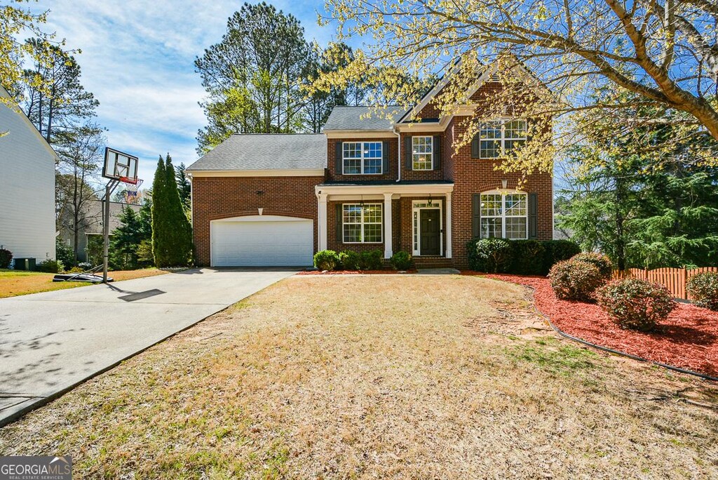 6065 N Gentlewind Ct N, Powder Springs, GA 30127 - view of front of home with fence, driveway, a front lawn, brick siding, and a garage