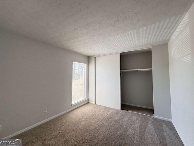 carpeted empty room featuring baseboards and a textured ceiling