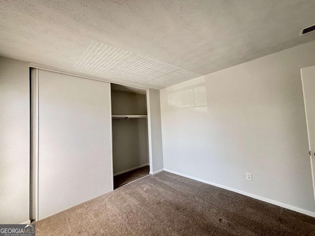 unfurnished bedroom featuring baseboards, a closet, carpet floors, and a textured ceiling