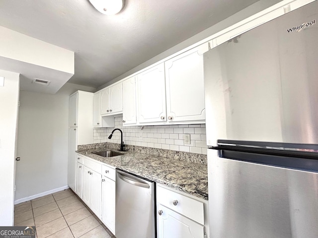 kitchen with decorative backsplash, white cabinets, visible vents, baseboards, and a sink