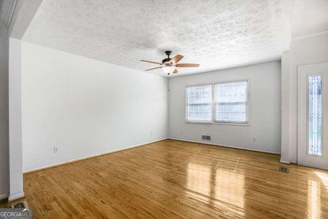 spare room featuring visible vents, wood finished floors, ceiling fan, and a textured ceiling
