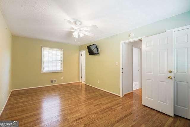 empty room featuring visible vents, a ceiling fan, and wood finished floors