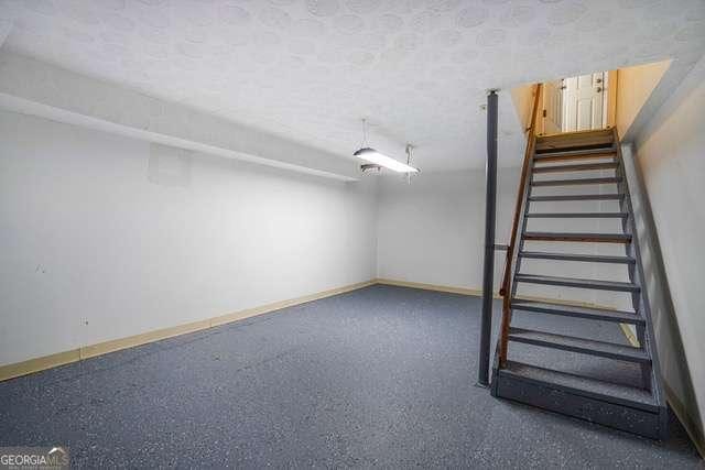 stairway with speckled floor, baseboards, and a textured ceiling