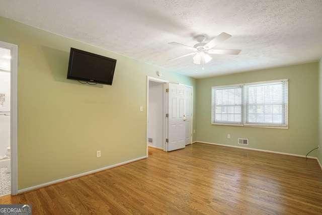 unfurnished bedroom with baseboards, visible vents, a textured ceiling, and wood finished floors