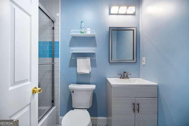 full bath with bath / shower combo with glass door, toilet, and vanity