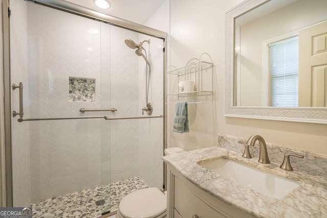 full bathroom featuring toilet, a stall shower, and vanity