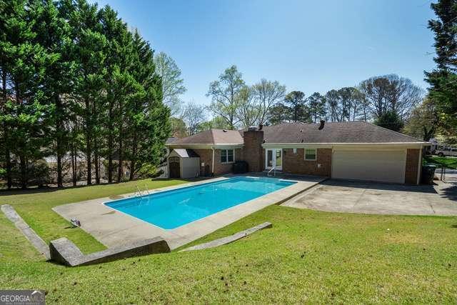 pool with an outdoor structure, a storage shed, a patio area, and a lawn