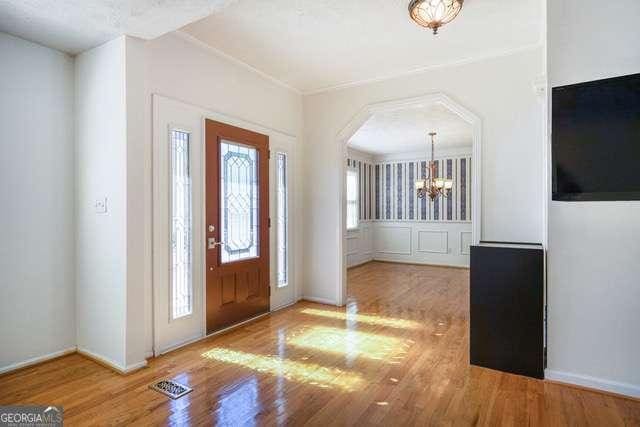 entryway featuring an inviting chandelier, visible vents, arched walkways, and wood finished floors